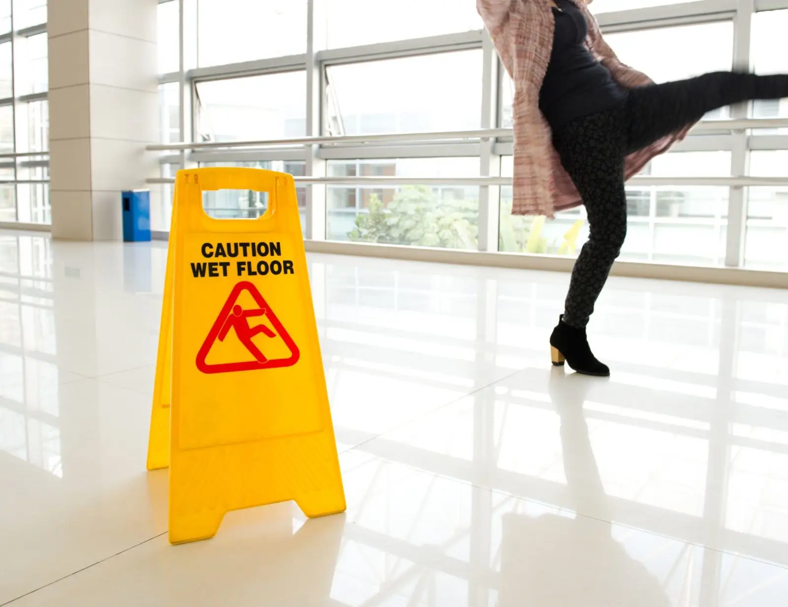 Slip and fall accident with caution wet floor sign and injured person