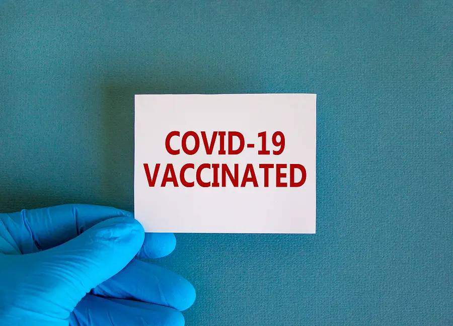 COVID-19 vaccinated card held by a gloved hand, relevant to CDC guidelines for cruise ships.