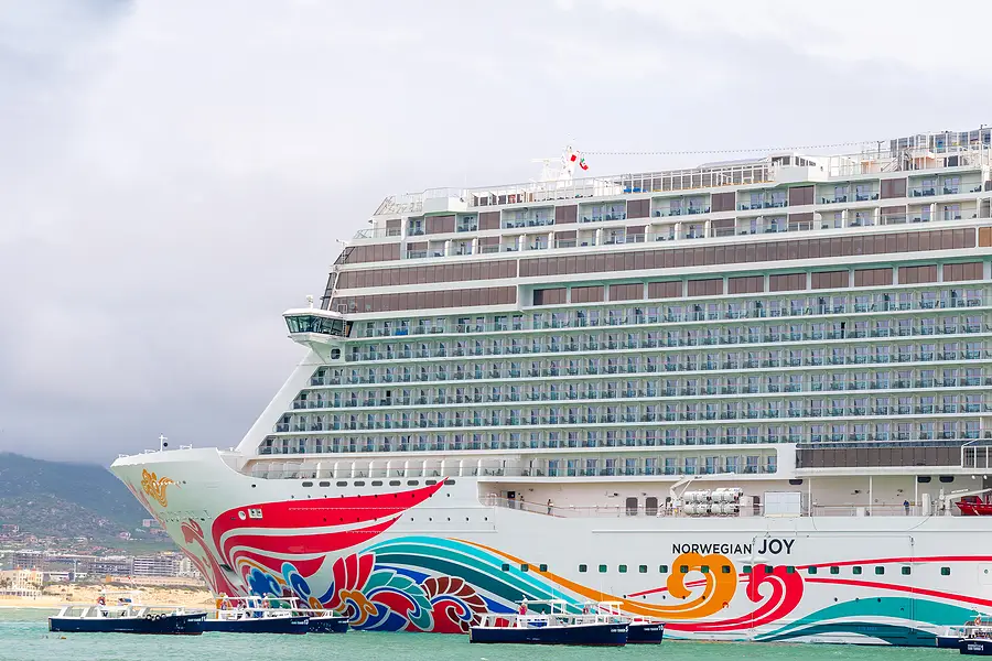 Norwegian Joy cruise ship docked in port, showcasing vibrant hull design and balconies, highlighting cruise travel options and maritime safety considerations.