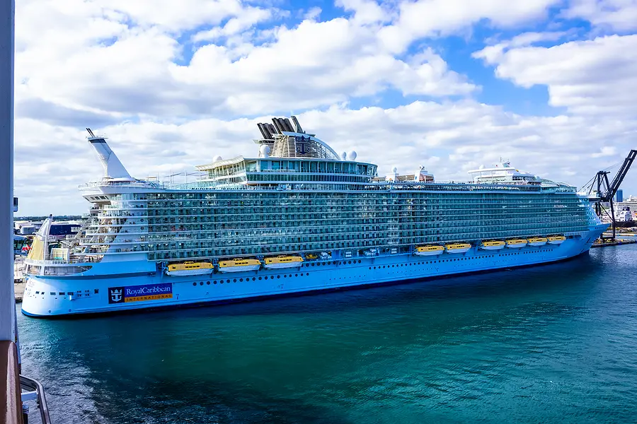 Royal Caribbean cruise ship Wonder of the Seas docked in port, showcasing its massive structure and vibrant blue exterior against a cloudy sky.