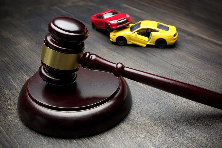 Gavel on wooden surface with toy cars representing automobile accidents and legal matters in personal injury law.