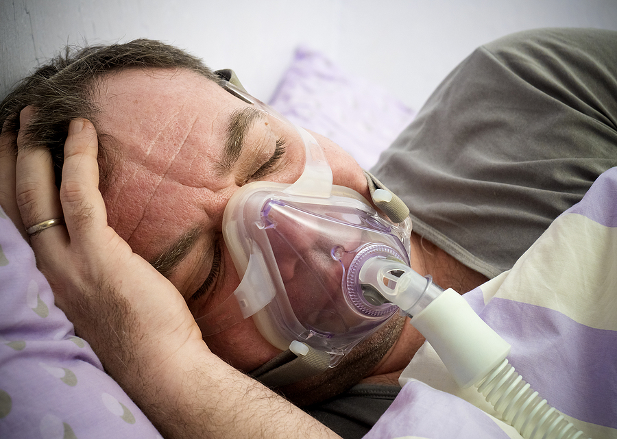man lying on bed with sleeping apnea and cpap machine