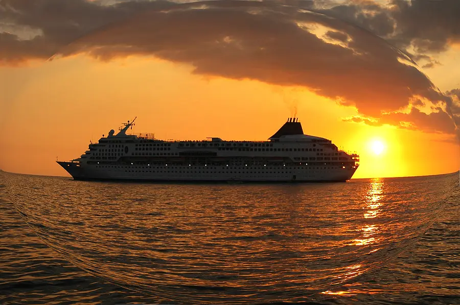 Cruise ship silhouette against a vibrant sunset over the ocean, symbolizing the departure of Virgin Voyages' Scarlet Lady from Port Miami.