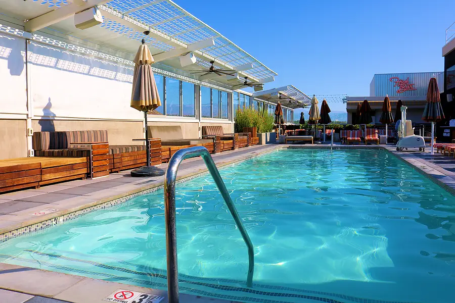 Rooftop pool with clear blue water, lounge chairs, and umbrellas, reflecting a sunny day, relevant to cruise ship leisure and safety discussions.