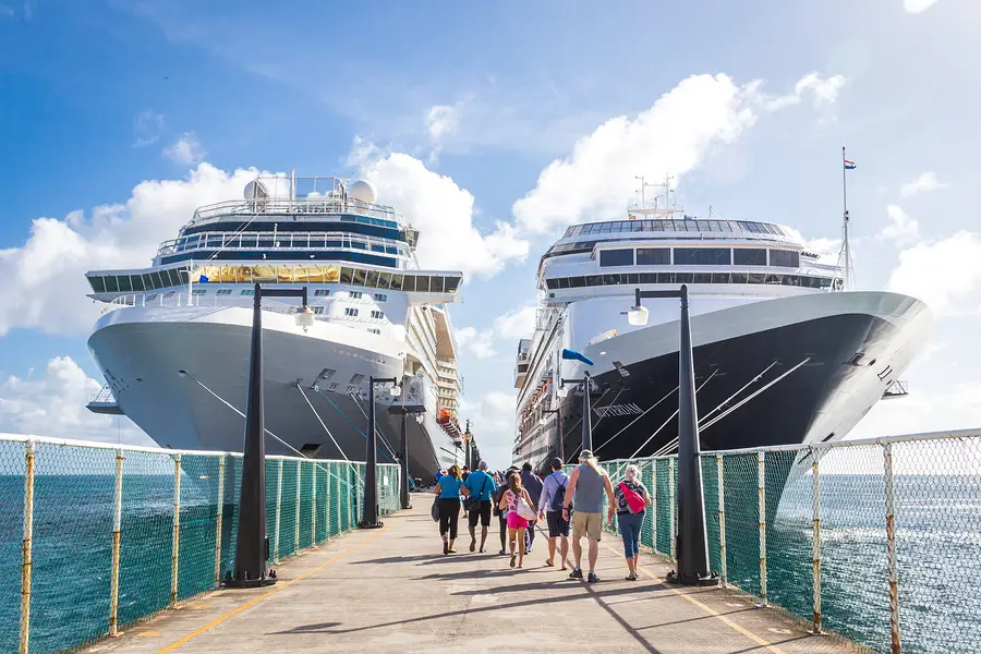 Cruise ships docked at a pier with passengers walking, highlighting the cruise industry and travel experiences.