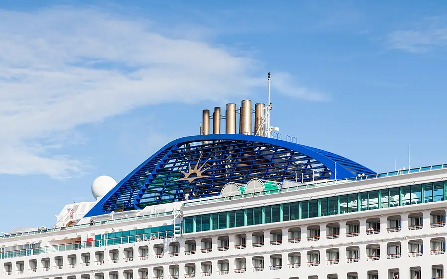 Cruise ship deck featuring distinctive blue design and smokestacks against a clear sky, relevant to discussions on cruise lines and safety regulations.