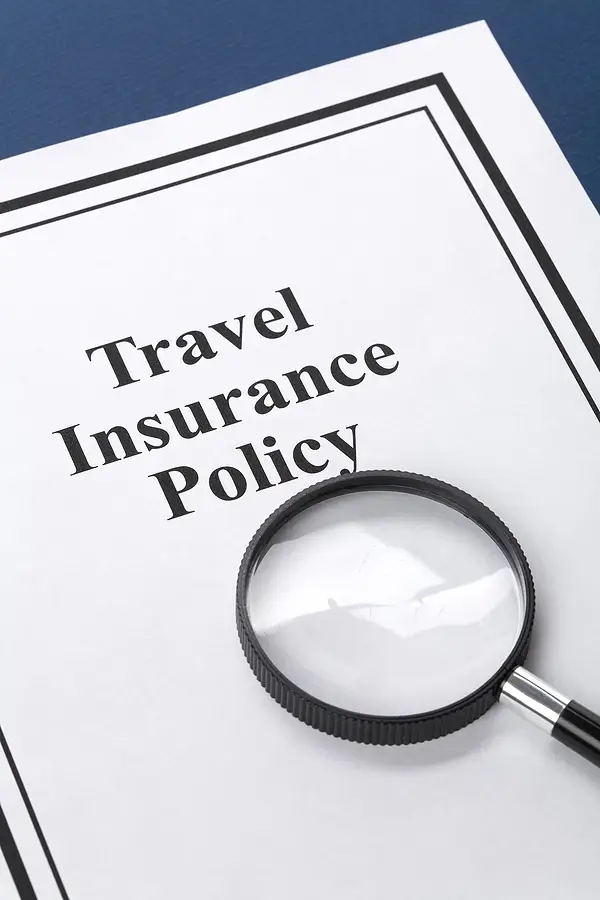 Travel insurance policy document with magnifying glass, emphasizing the importance of understanding coverage for cruise trips and travel safety.