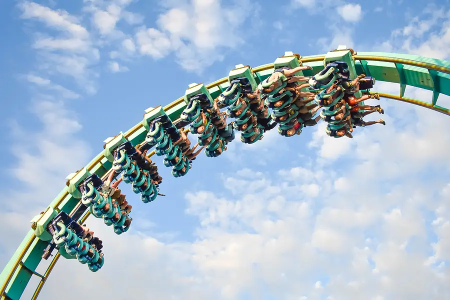 Roller coaster with riders experiencing thrills against a blue sky, highlighting the excitement of theme parks in Florida.