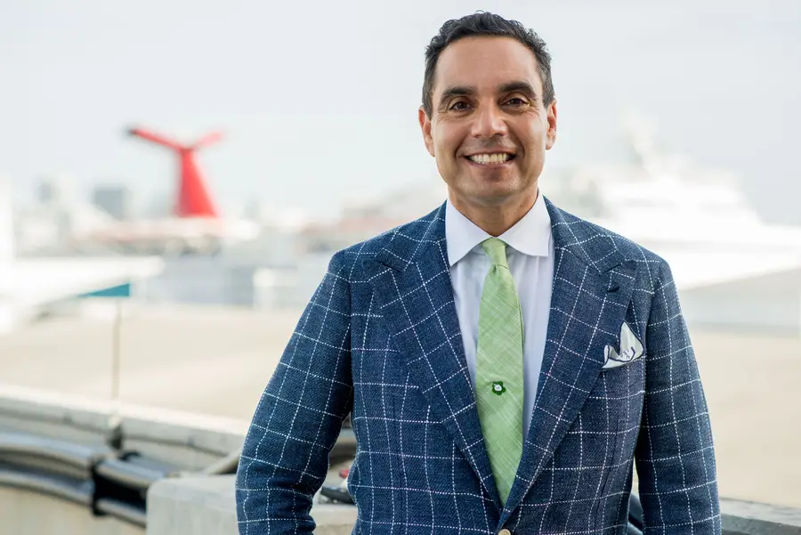Man in a suit standing near a cruise ship with a red funnel, representing maritime law and personal injury advocacy.