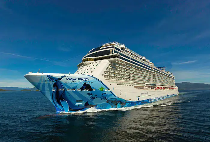 Norwegian Cruise Line's Norwegian Prima sailing in clear waters, featuring vibrant Wyland marine art on the hull, symbolizing luxury cruising experiences.