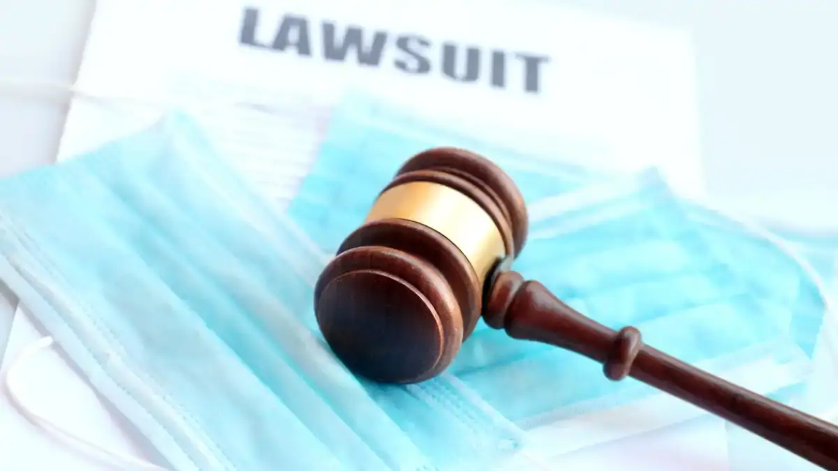 Gavel resting on medical face masks and lawsuit document, symbolizing legal actions related to COVID-19 and personal injury cases.