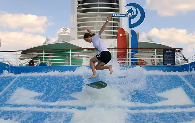 Person surfing on FlowRider attraction aboard a cruise ship, showcasing onboard entertainment and activities related to maritime leisure.
