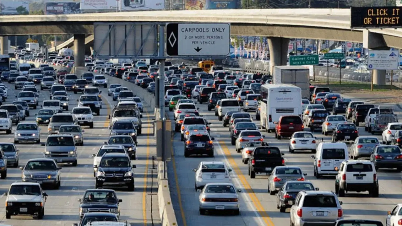 Heavy traffic congestion on a Florida highway during peak travel season, with numerous vehicles and a "Carpools Only" sign, illustrating the anticipated busy road conditions around Thanksgiving.