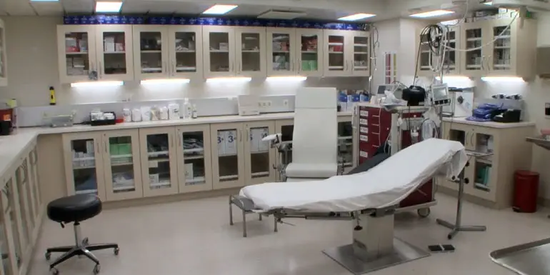 Cruise ship medical emergency room with examination table, medical equipment, and storage cabinets for supplies.