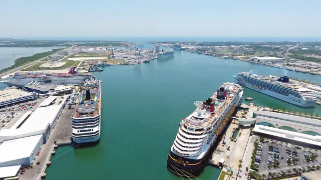 Aerial view of Port Canaveral with multiple cruise ships docked, showcasing the bustling cruise terminal and surrounding infrastructure in Brevard County, Florida.