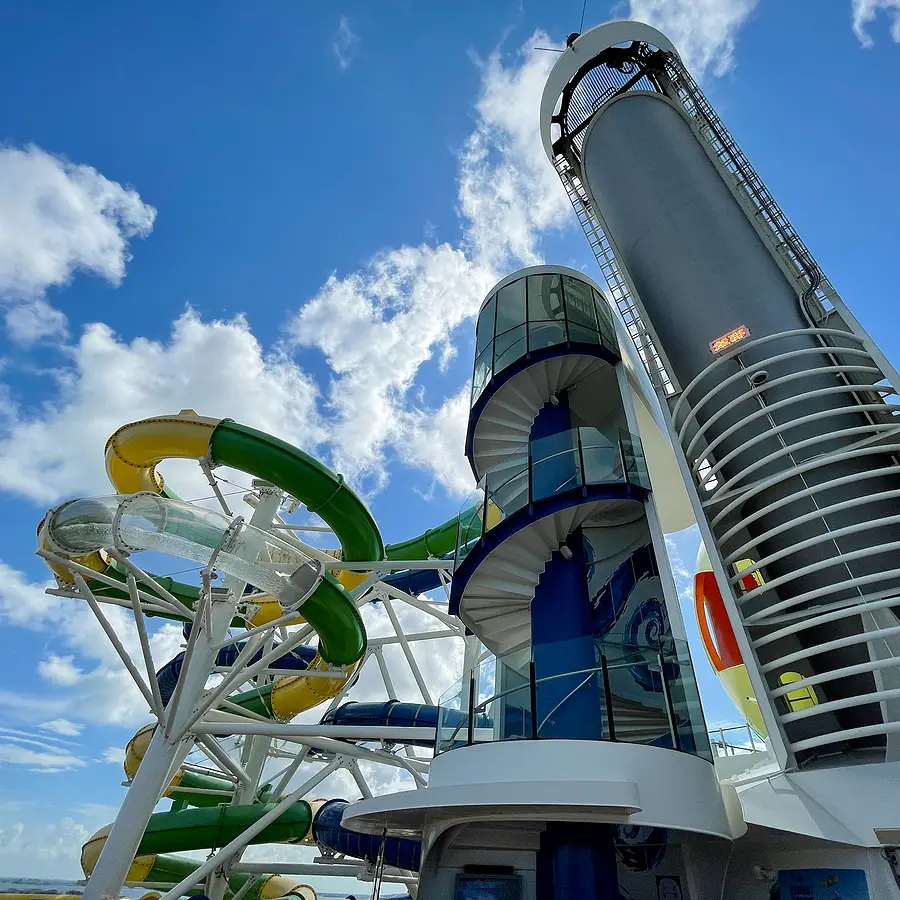 Cruise ship water park featuring colorful water slides and a spiral staircase, emphasizing Royal Caribbean's innovative leisure amenities.