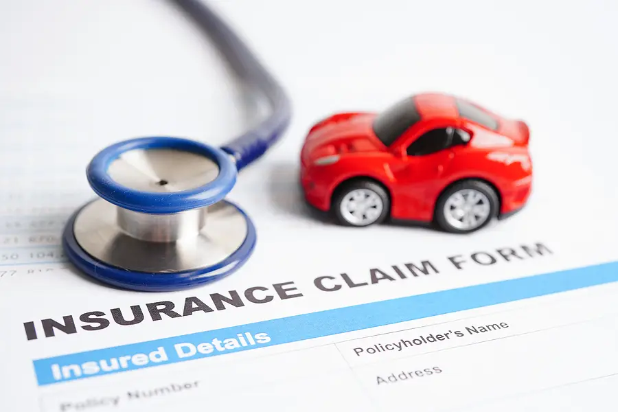 Stethoscope and toy car on an insurance claim form, symbolizing personal injury and car accident insurance claims in Florida.