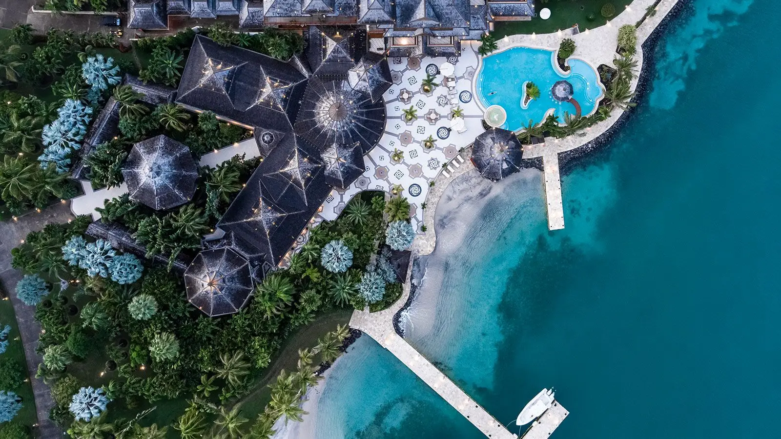 Aerial view of a luxurious private Caribbean island resort featuring a pool, beach, and lush greenery, highlighting cruise ship destinations and vacation relaxation.
