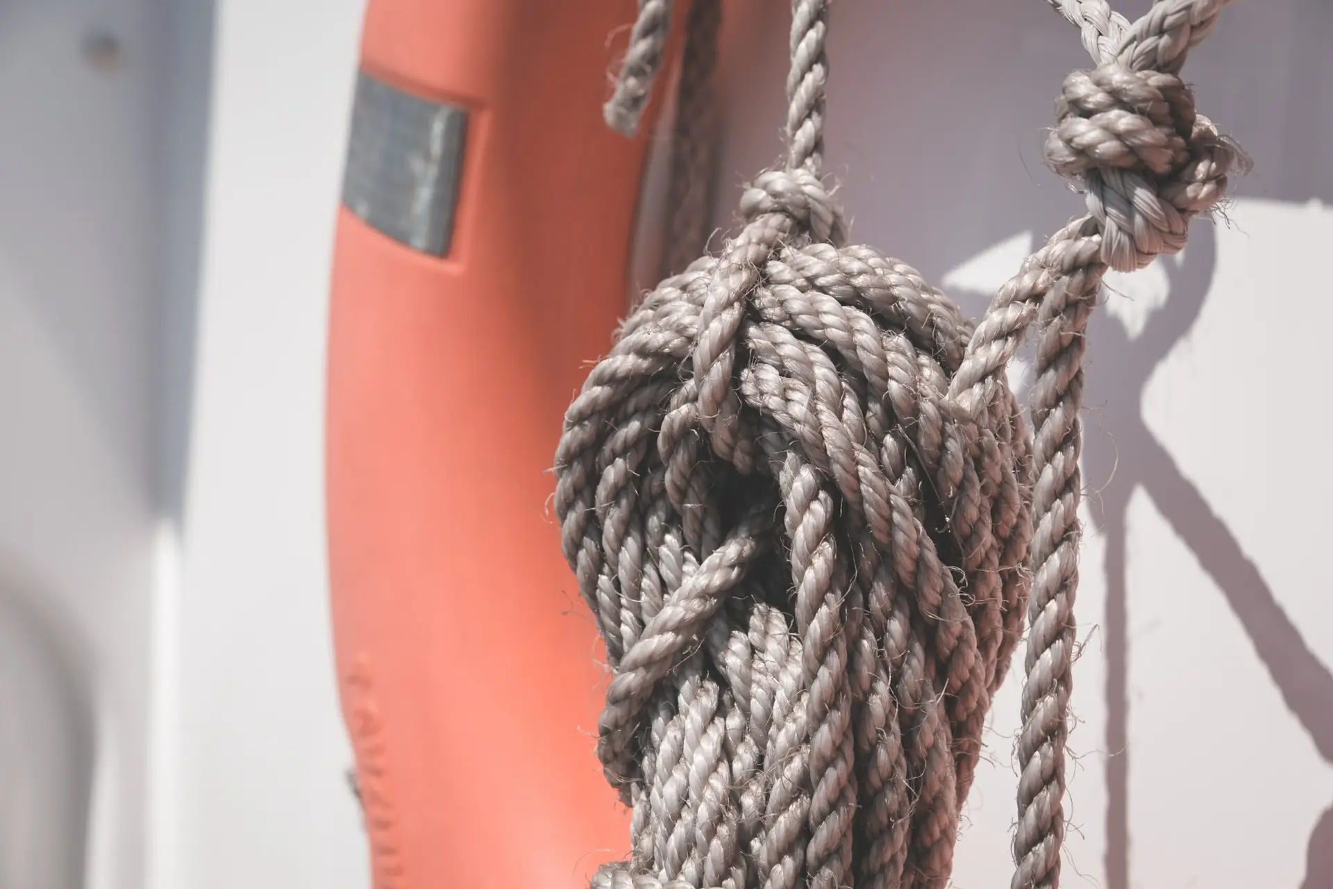 Rope coiled near an orange life preserver on a ship, emphasizing maritime safety and legal insights from Aronfeld Trial Lawyers.