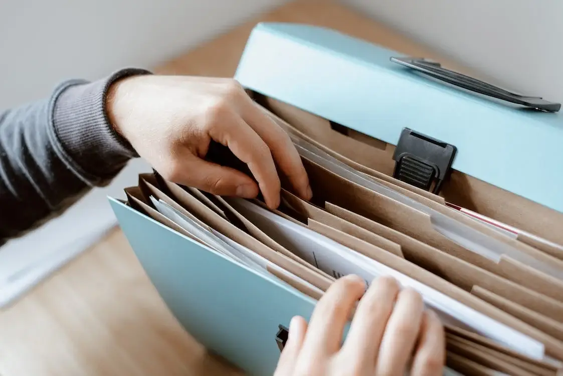 Person organizing documents in a blue file folder, emphasizing legal paperwork and safety tips related to personal injury and maritime law.