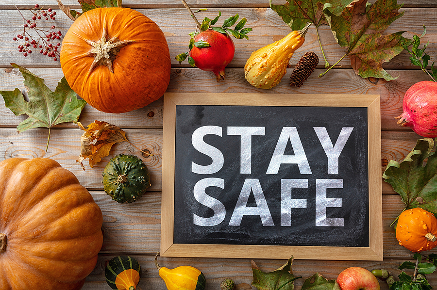 stay safe message and thanksgiving pumpkins against wooden backg