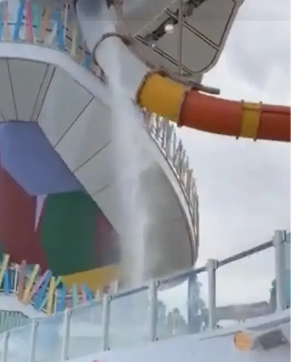 Water gushing from the damaged Frightening Bolt Waterslide on Royal Caribbean's Icon of the Seas, showcasing the broken panel and colorful design elements.