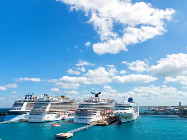 Cruise ships docked at a vibrant port under a blue sky with fluffy clouds, illustrating the maritime context of cruise-related incidents and legal representation.