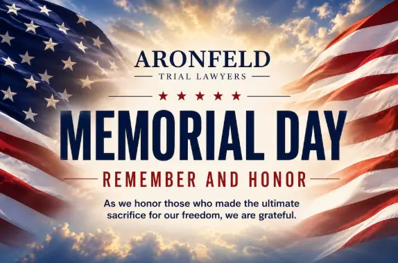 Aronfeld Trial Lawyers Memorial Day tribute and American flag background representing car accident and personal injury legal services.