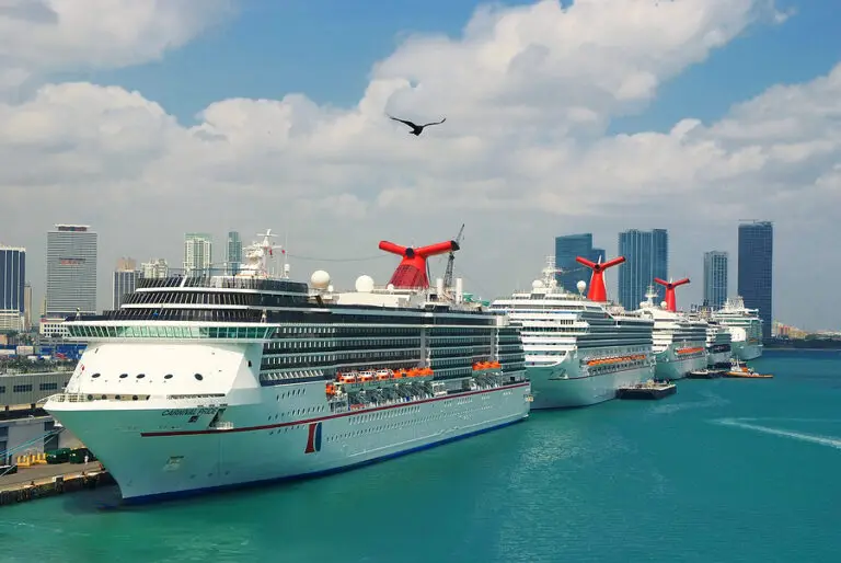 Multiple large cruise ships docked at the port of Miami with the city skyline
